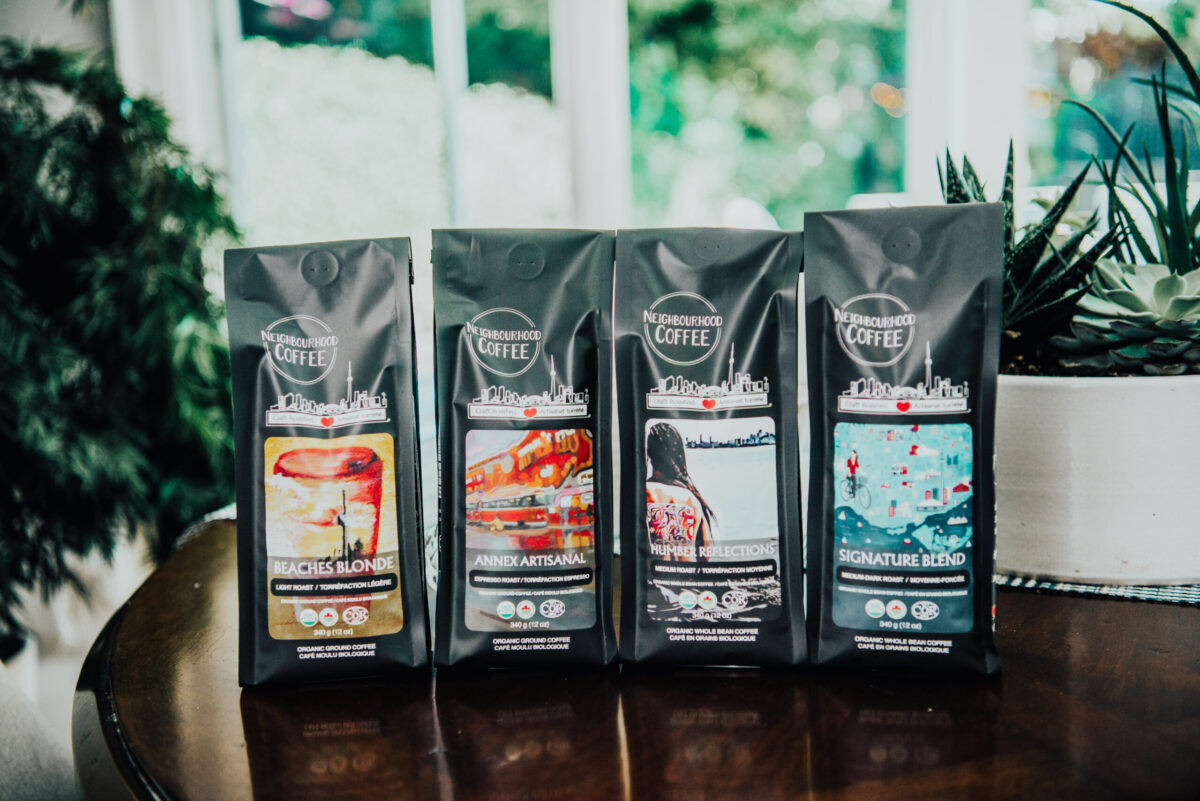Neighbourhood Coffee’s four roasts shown side by side, with the bags featuring colourful designs from local Canadian artists.