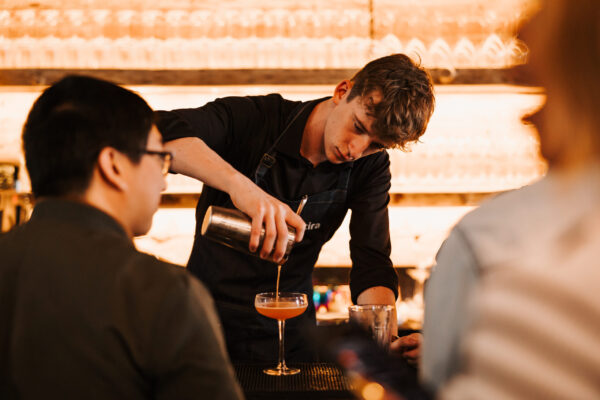 A bartender pouring a drink at a bar