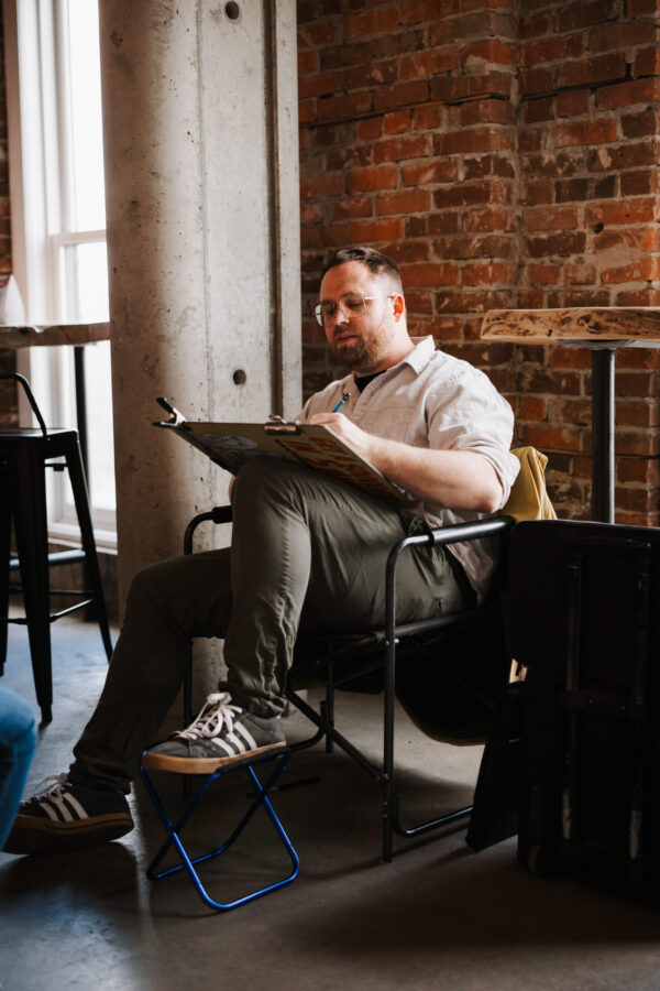 Sam Glassman sitting down drawing caricatures