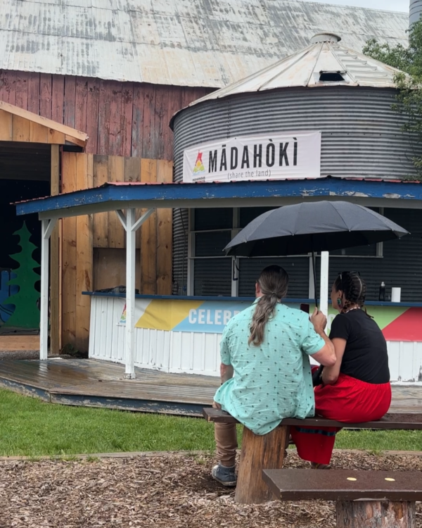 Two people sitting under an umbrella at the Summer Solstice Festival