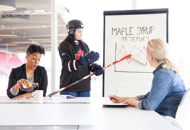 Colleague enjoys tasty glass of maple syrup during presentation by hockey player